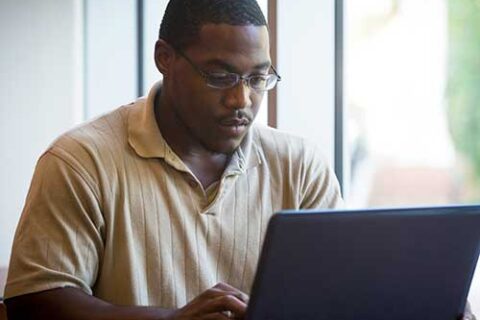 student writing on a laptop