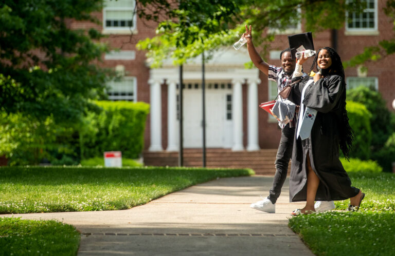 Two students walk across the Dell