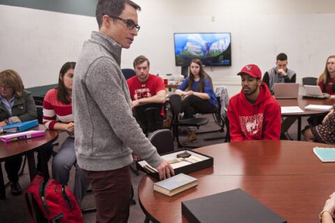 Professor Adam Dean teaching a group of students in a classroom.