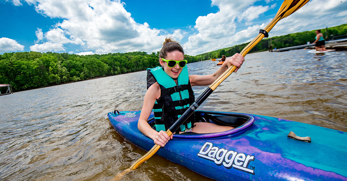 Student paddling down a river in a kayak.