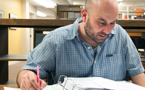 A male student working at a desk in front of a laptop