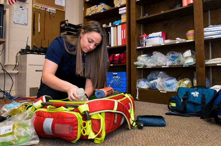 Delia LoSapio sitting on the floor, filling a bag with medical supplies