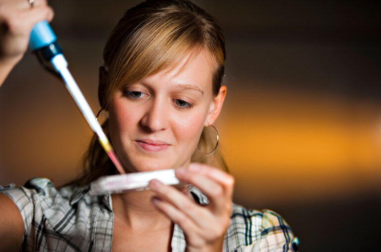 Alyson Black is using a pipette while conducting research