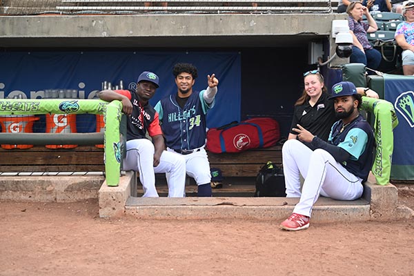 Shea Alheit '21, '23 MSAT in a baseball dugout with players.