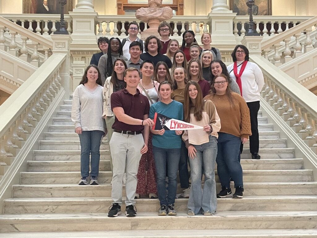 A group of students and two mentors stand on the steps of the Atlanta State Capitol.