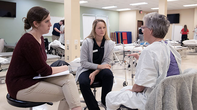 A patient with two DPT students in a physical therapy facility