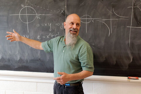 A professor teaching in front of a blackboard
