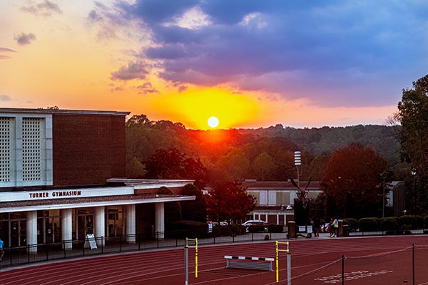 A brick athletic building and a track at sunset