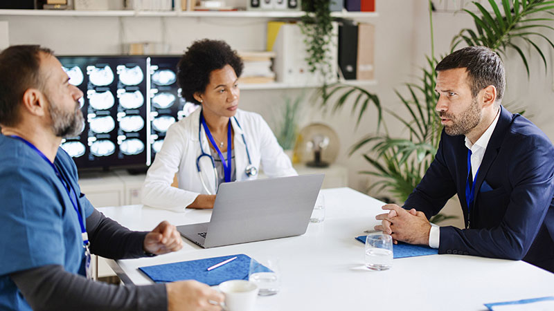 Three people sitting around a small conference table and talking