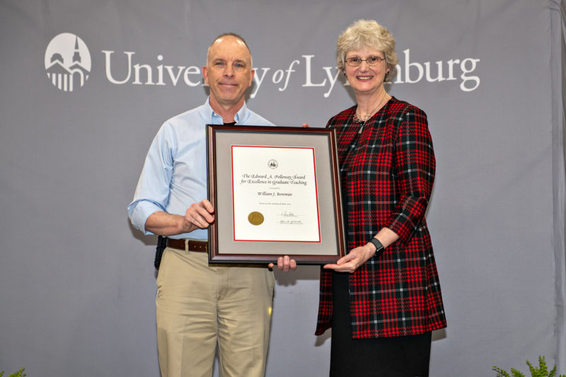 A white man and a white woman posing for a photo holding a framed certificate between them