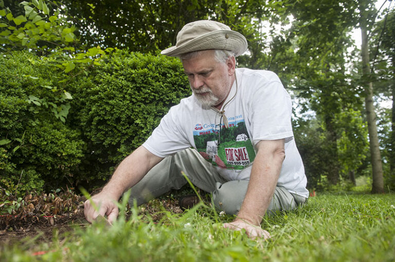 A man sits in the dirt digging a hole.