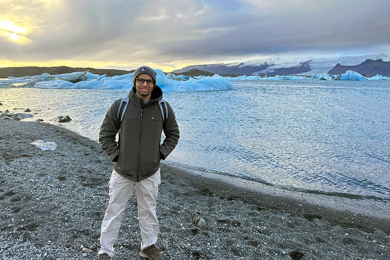 Vedant Patel standing outdoors near a body of water during a trip to Iceland