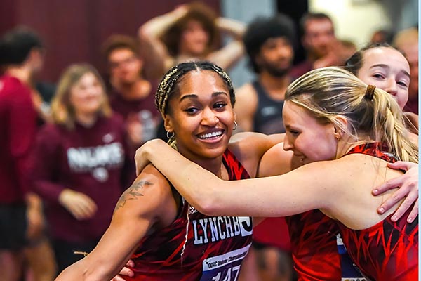 A black girl and a white girl in red track outfits smile and hug