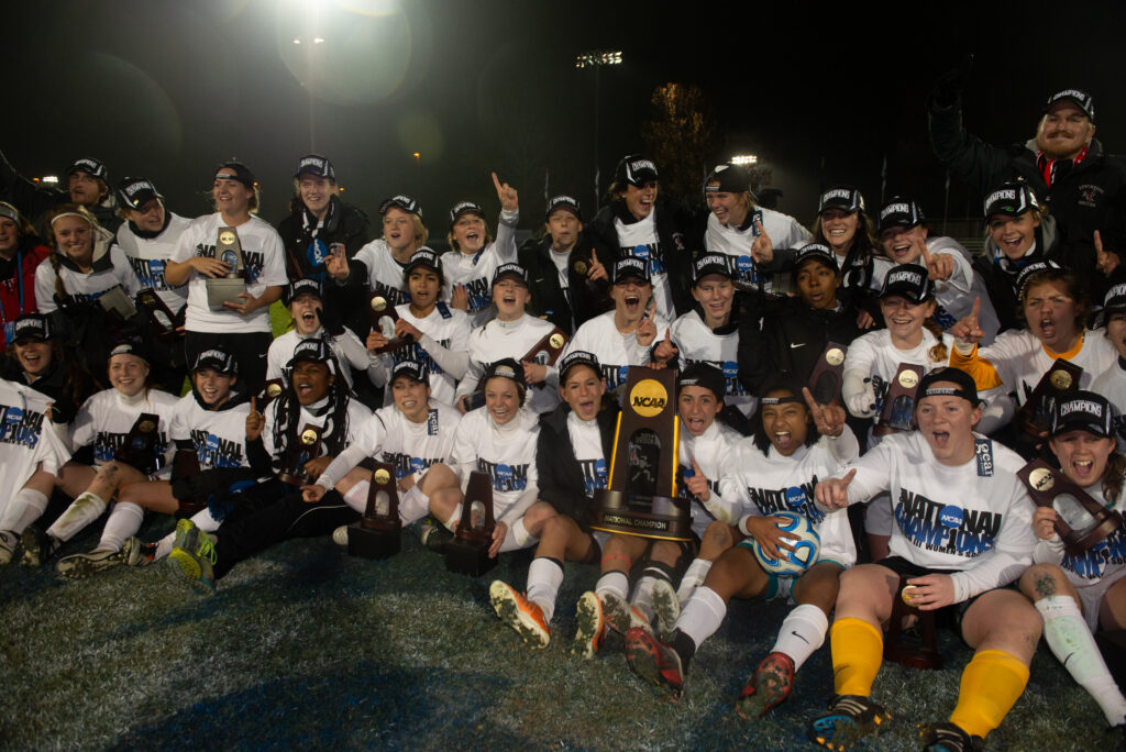 The 2014 Lynchburg College Women's soccer team poses with their trophies on the field.