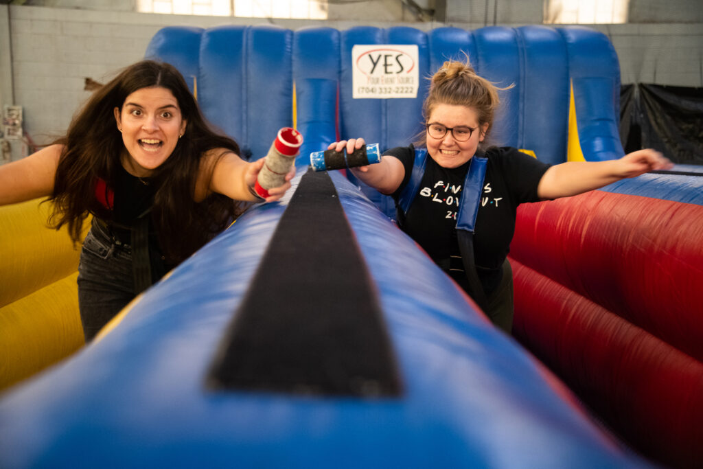 Two female students race along a blue innertube