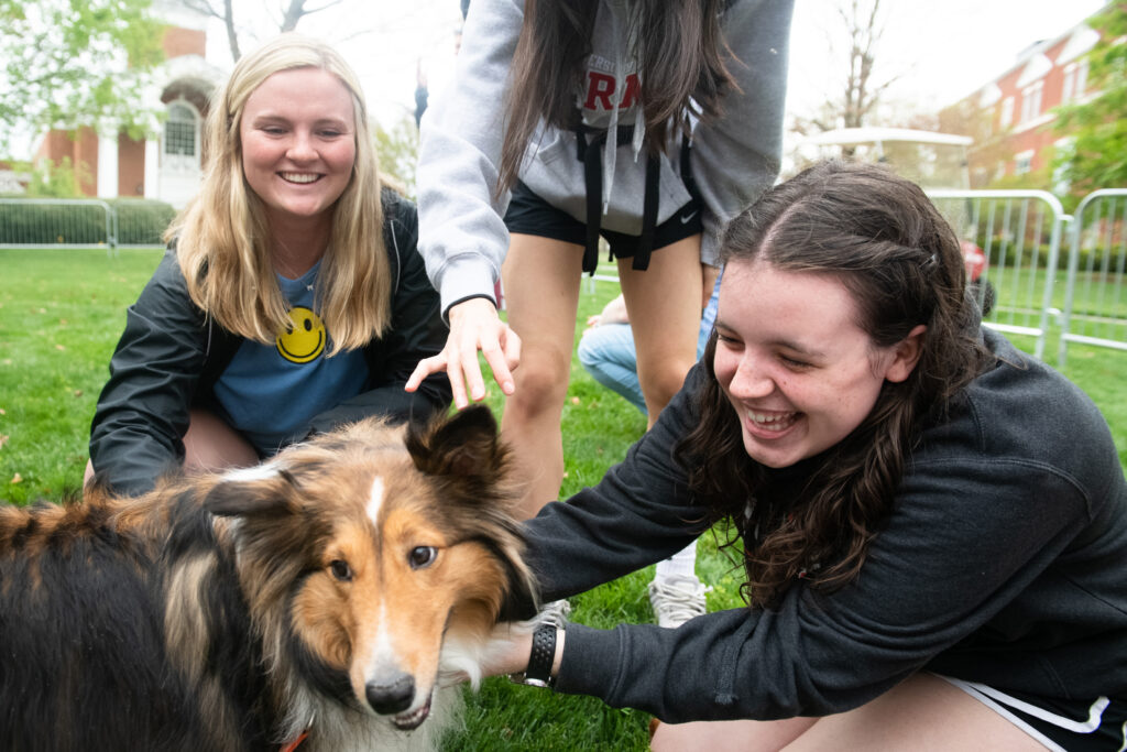two female students pet a dog