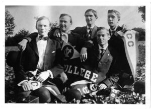 A group of male students pose holding Virginia Christian College flags.