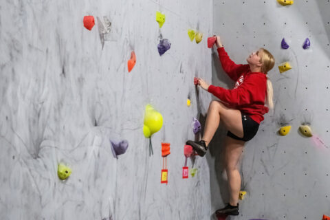 A female student climbing a rock wall.
