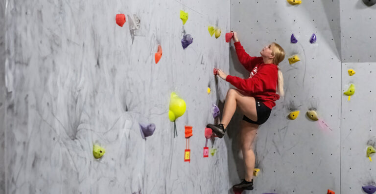 A female student climbing a rock wall.