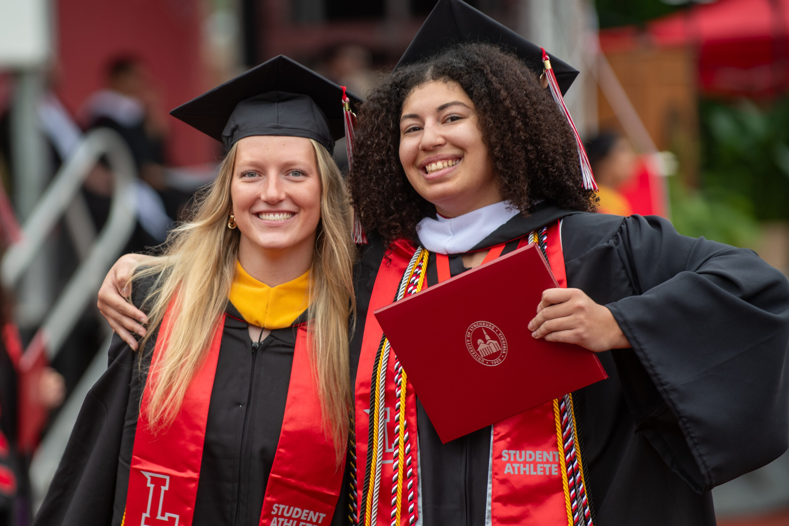 Two University of Lynchburg graduates, one holding a diploma