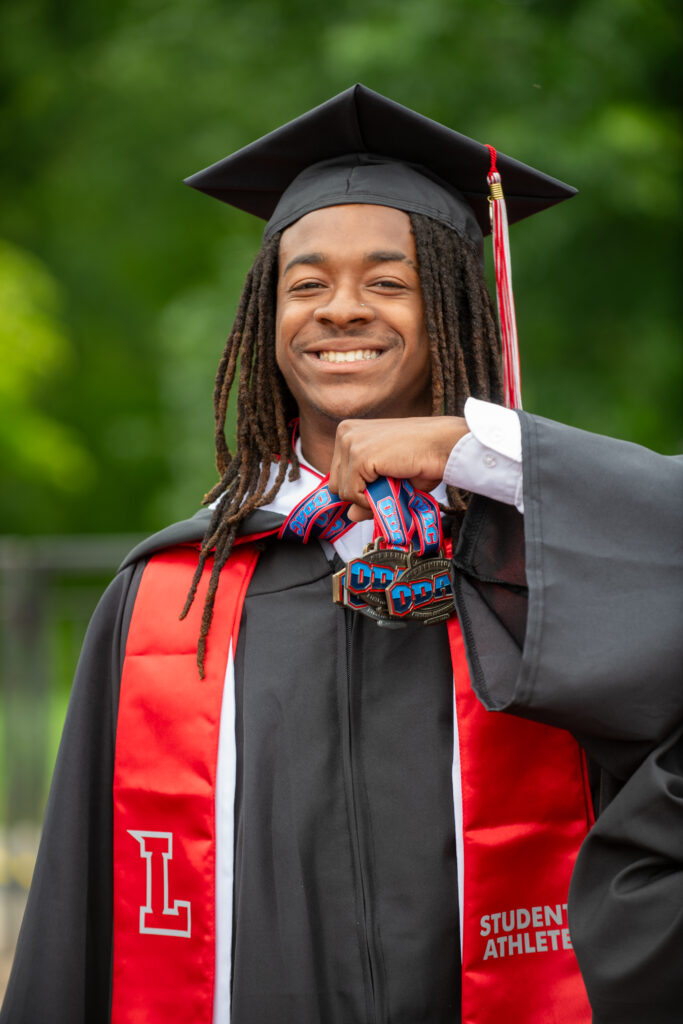 Student-athlete graduate holding ODAC medals.