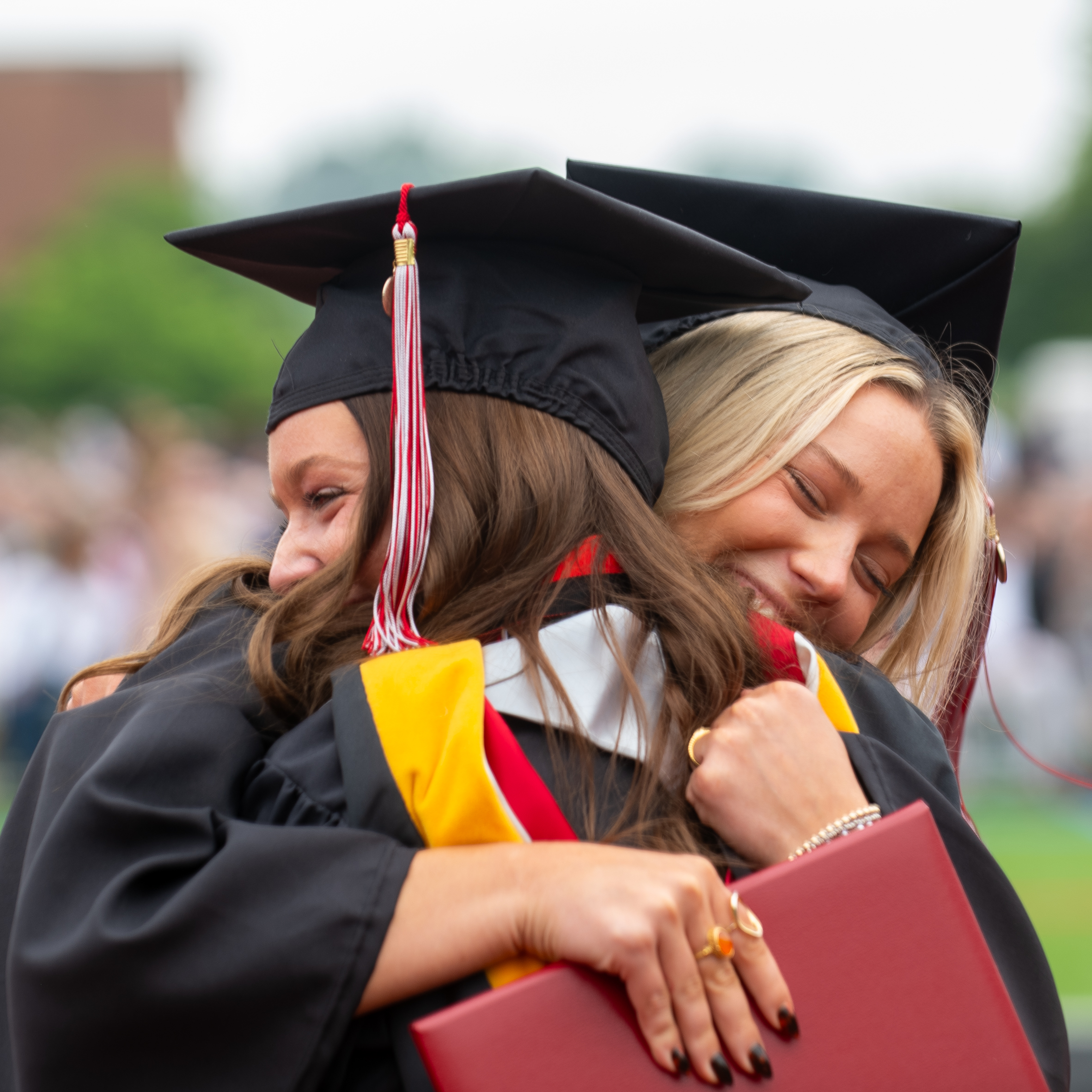 Graduates hug each other.