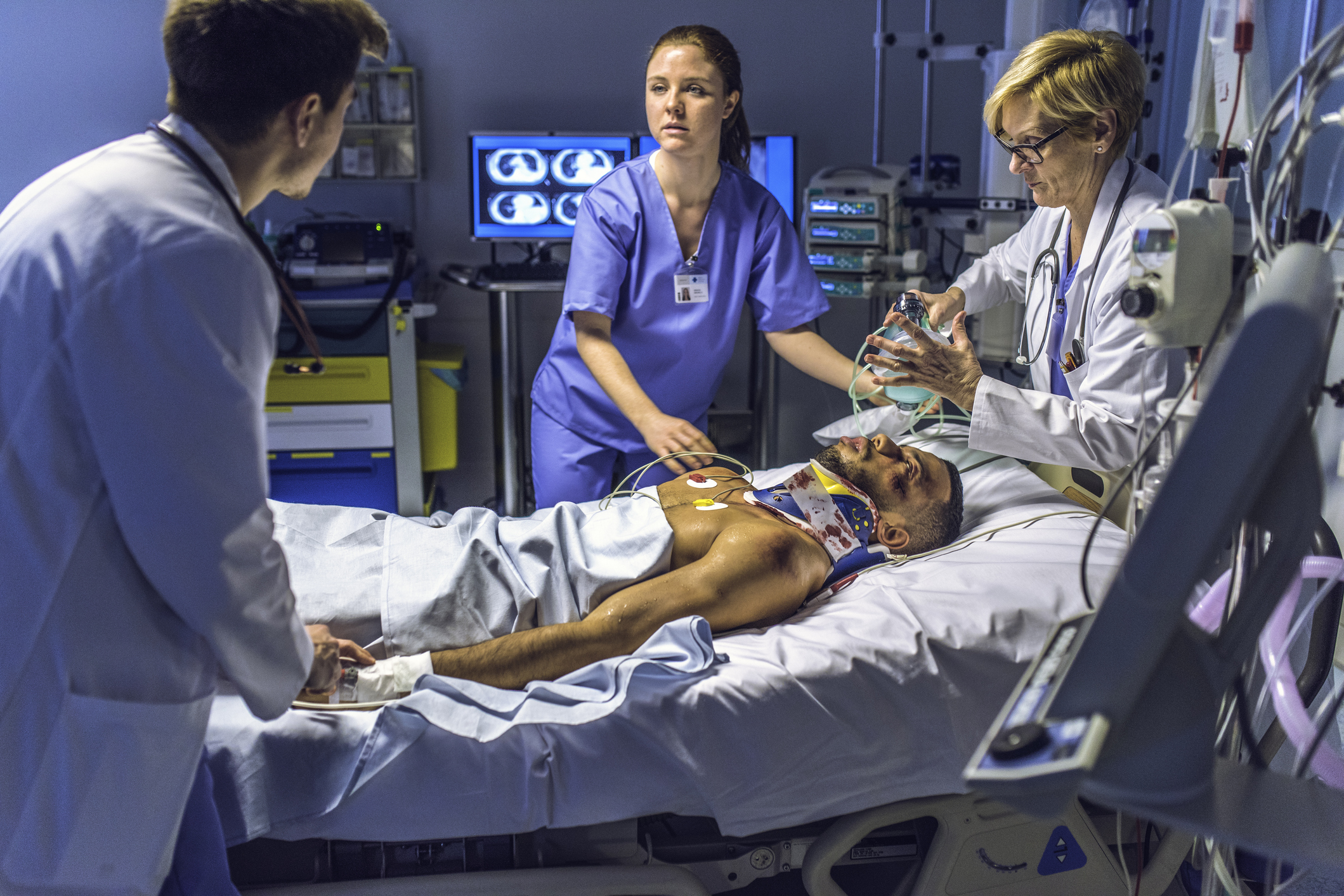 Female doctor holding a resuscitation bag on the face of a patient in emergency room.