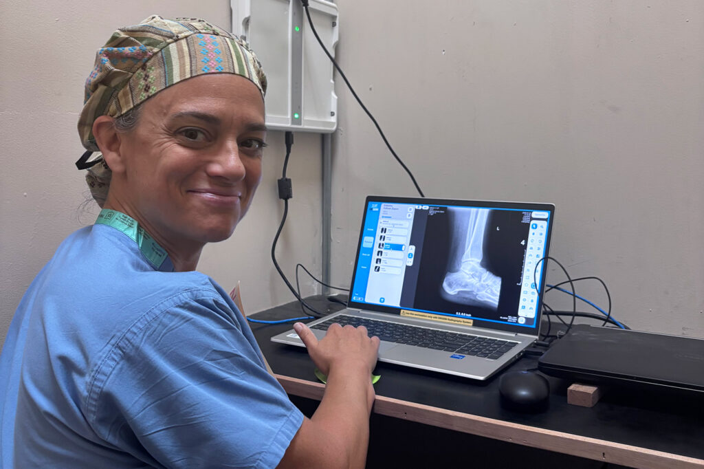 Dr. Bryn Kroto sitting a desk with a laptop displaying an x ray.