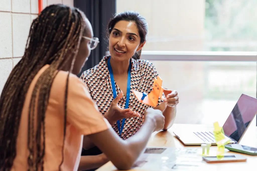 Two women speaking next to a computer