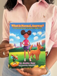 Justice Gray holding her children's book, “What is Normal, Anyway?: Because the Best Kind of Normal is Being You”