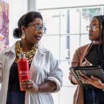 Two women talking and walking through a gallery.