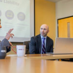 A group of professionals hold a conversation around a table.
