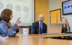 A group of professionals hold a conversation around a table.