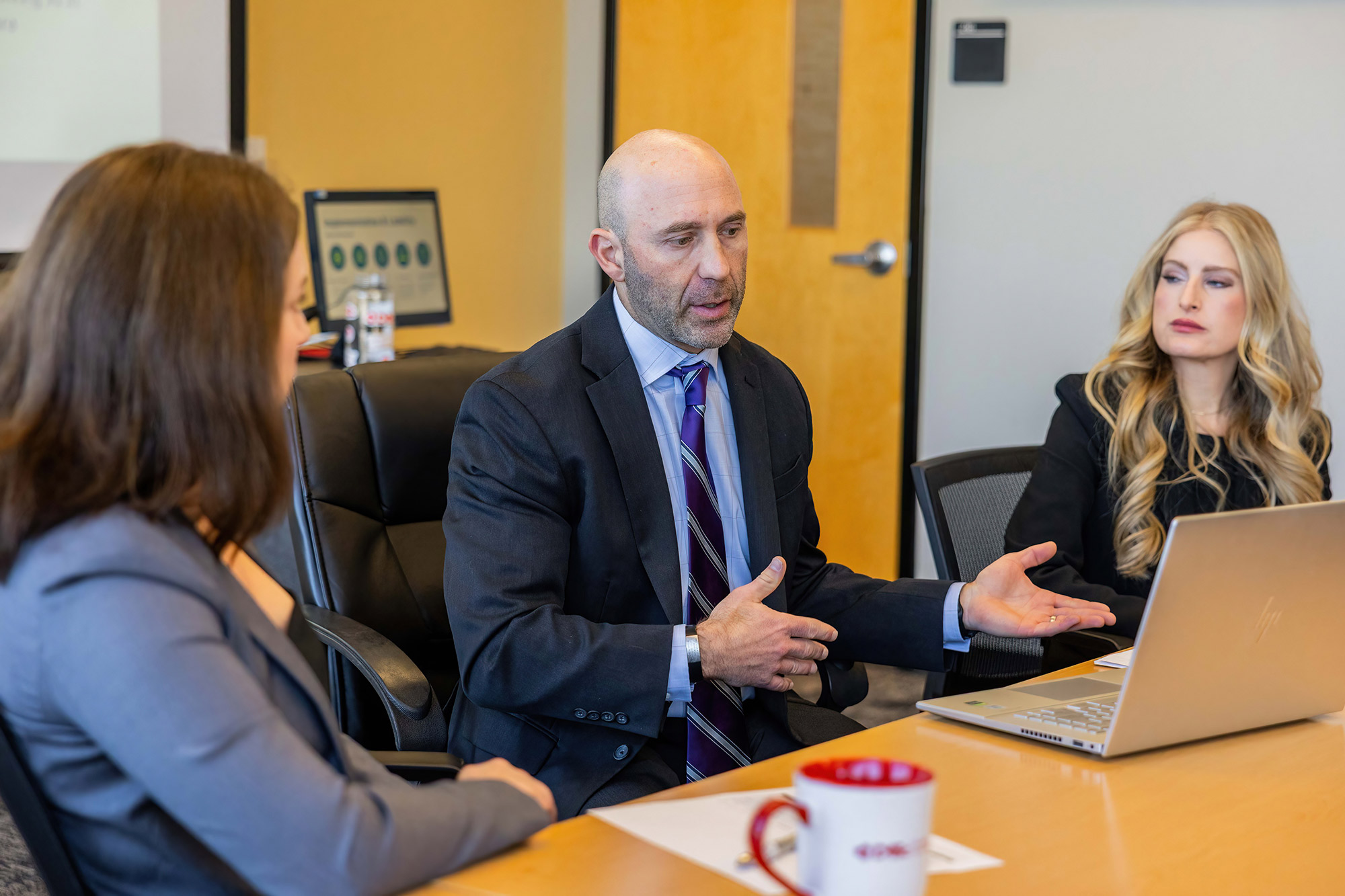 A group of professionals hold a conversation around a table.