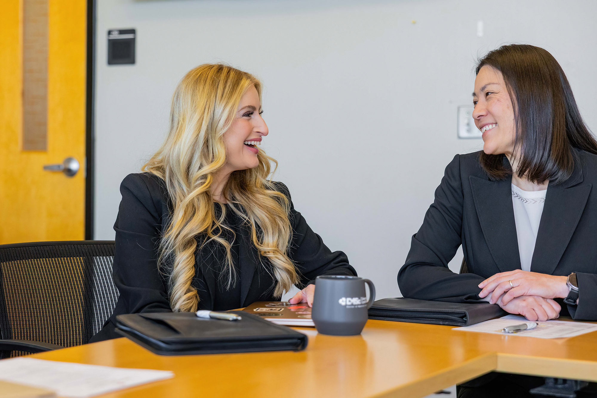 Two women sitting at a conference table.