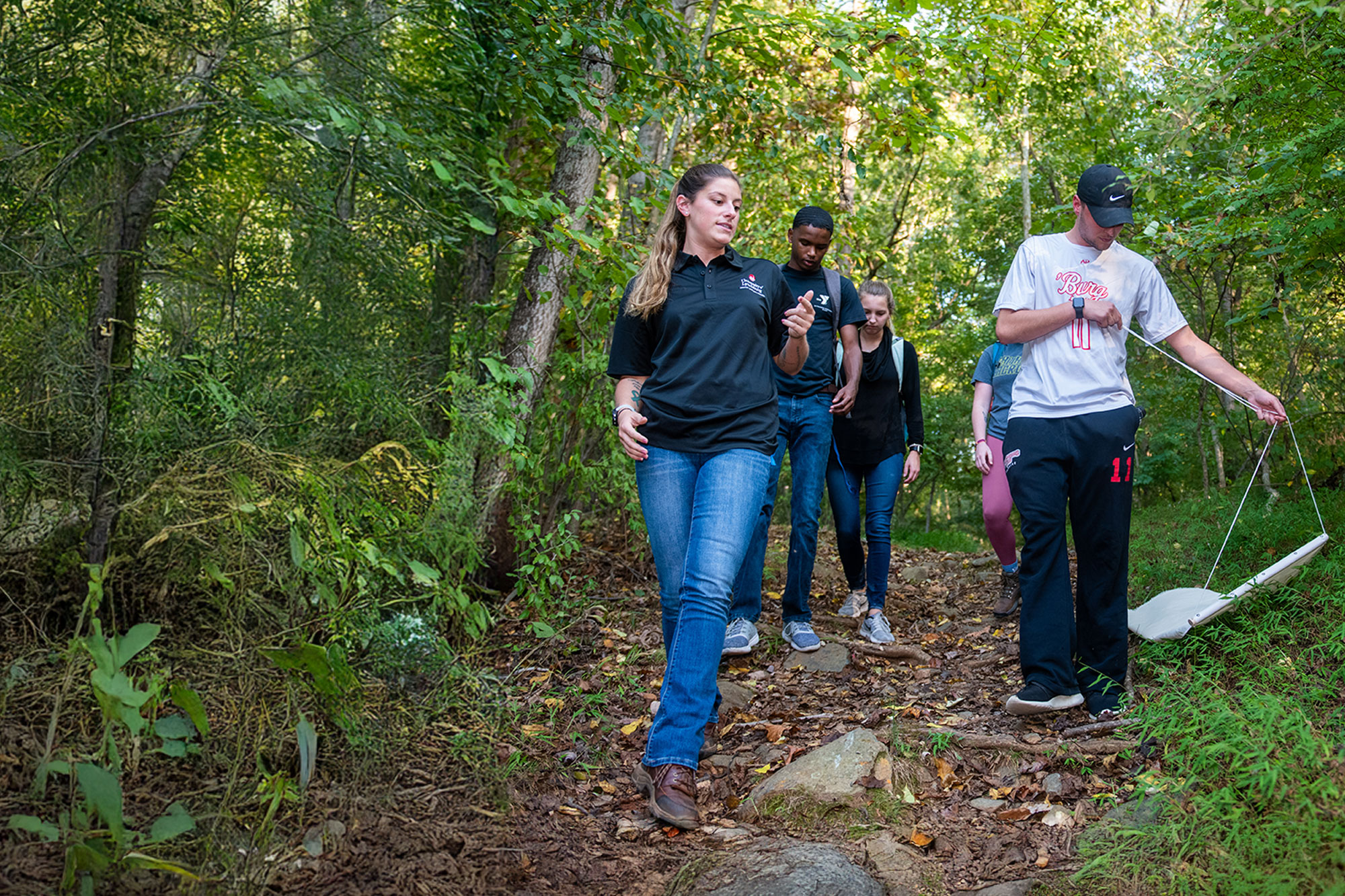 Bachelor of Applied Public Health students conduct fieldwork on a wooded trail, collecting environmental data.