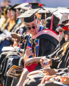 A white man wearing academic regalia looks at the camera.