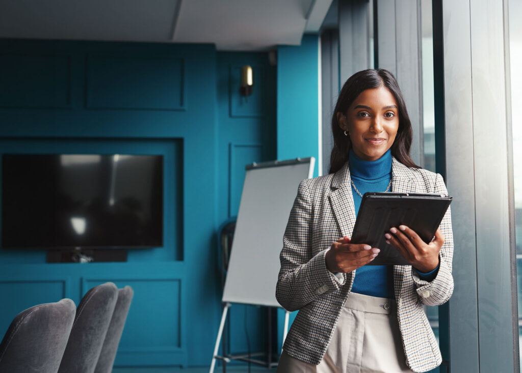 A woman wearing a gray suit holding a tablet.