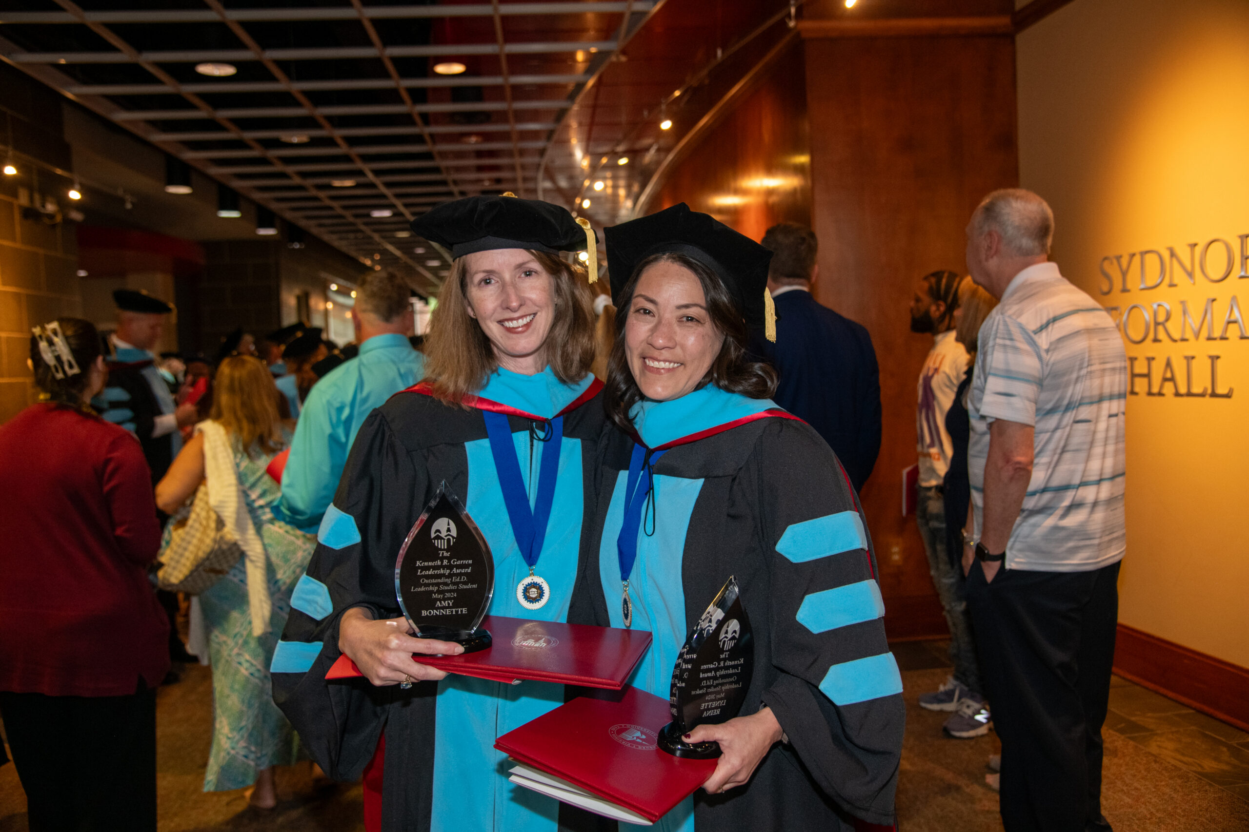 two female graduated of the doctor of education program dressed in their regalia.
