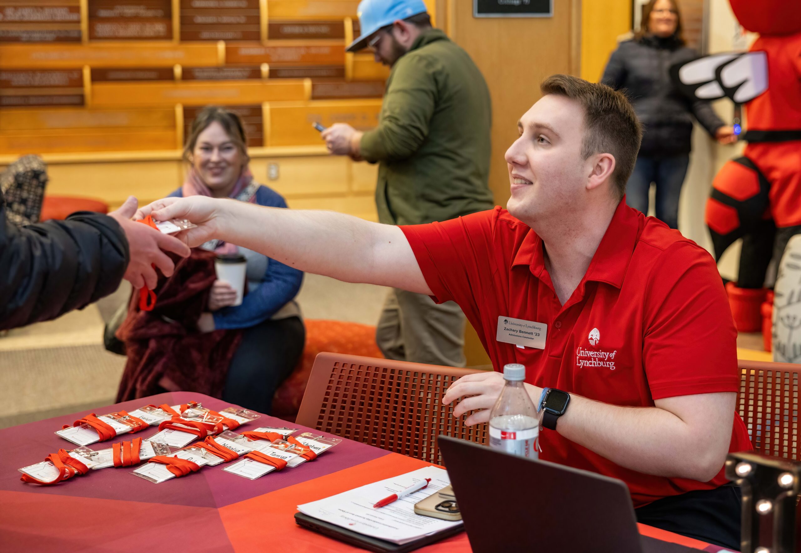 admissions counselor smiling and handing information to a prospective student