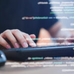 close up programmer student man hand typing on keyboard at computer desktop to input code language into software for study bug and defect of system in classroom , development of technology concept