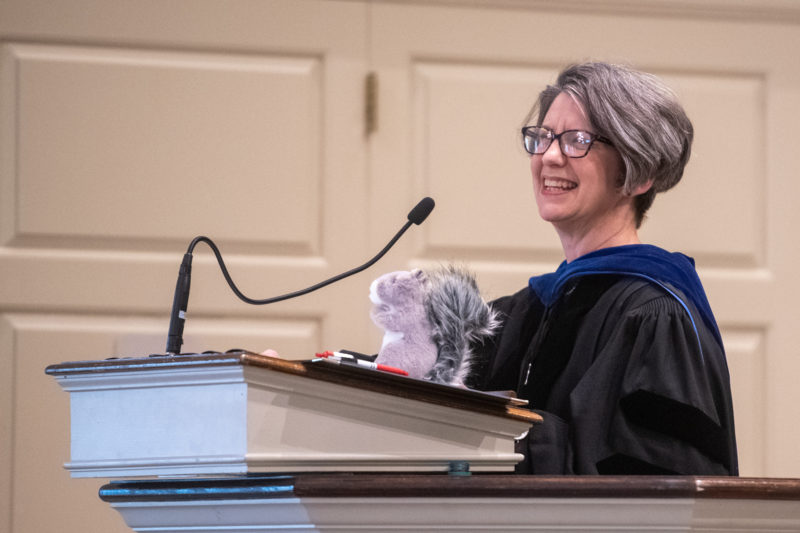 Dr. Amy Merrill Willis at podium with stuffed squirrel, 2023 Baccalaureate