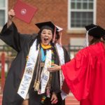 Student holds diploma overhead, celebrates at 2023 Commencement.