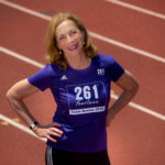 Kathrine Switzer standing on a track with a 261 Fearless shirt