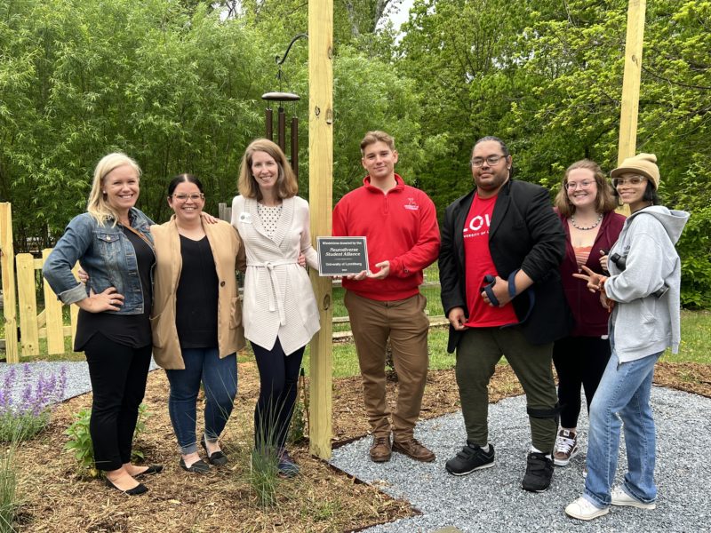 Members of the Neurodiverse Student Alliance pose with Amy Bonnette, executive director of Camp Kum-Ba-Yah Nature Center. The affinity group was there in April to donate a windchime for the center’s new sensory garden. Pictured (left to right) are Dr. Cindi Spaulding, Meg Dillon ’17 MEd, Amy Bonnette, Aaron Albright ’24 MEd, Laurence Walker ’24, Corrine West ’24, and Donzailya Berg ’23. 