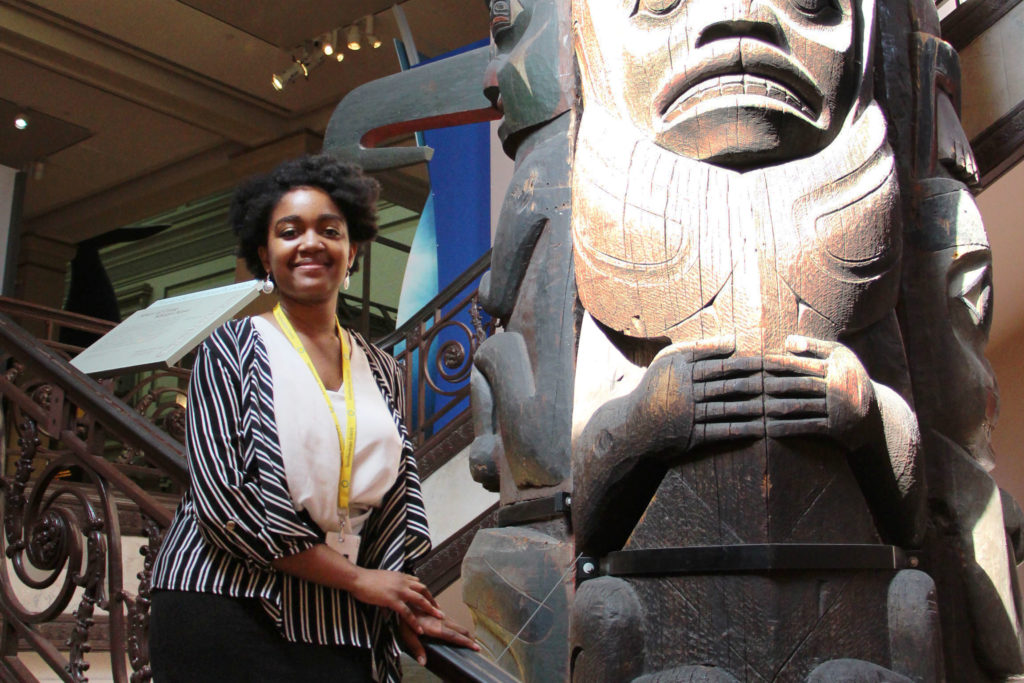 Ahsani Parker stands in front of a totem pole in the natural history museum