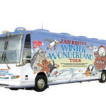 A tour bus decorated with children's book illustrations and the words "Jan Brett's Winter Wonderland Tour"