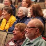 A group of older white people in an auditorium