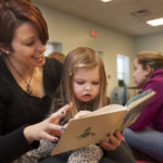 an education student reads to a young girl