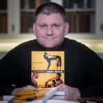 Eric Goff holding a copy of his book "The Physics of Krav Maga"